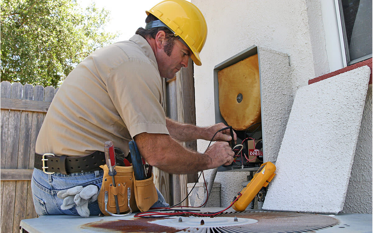 A technician tests the wiring on an outdoor unit